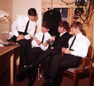 Volume 2. Page 85, Picture 8. 1963. The pop group “The Beatles” read a letter in their dressing room. Pictured left to right: Paul McCartney, George Harrison, John Lennon and Ringo Starr.