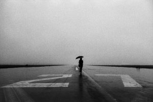 Lone person with umbrella in the rain on runway