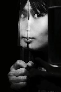Portrait Of Woman Holding Kitchen Knife With Reflection Against Black Background
