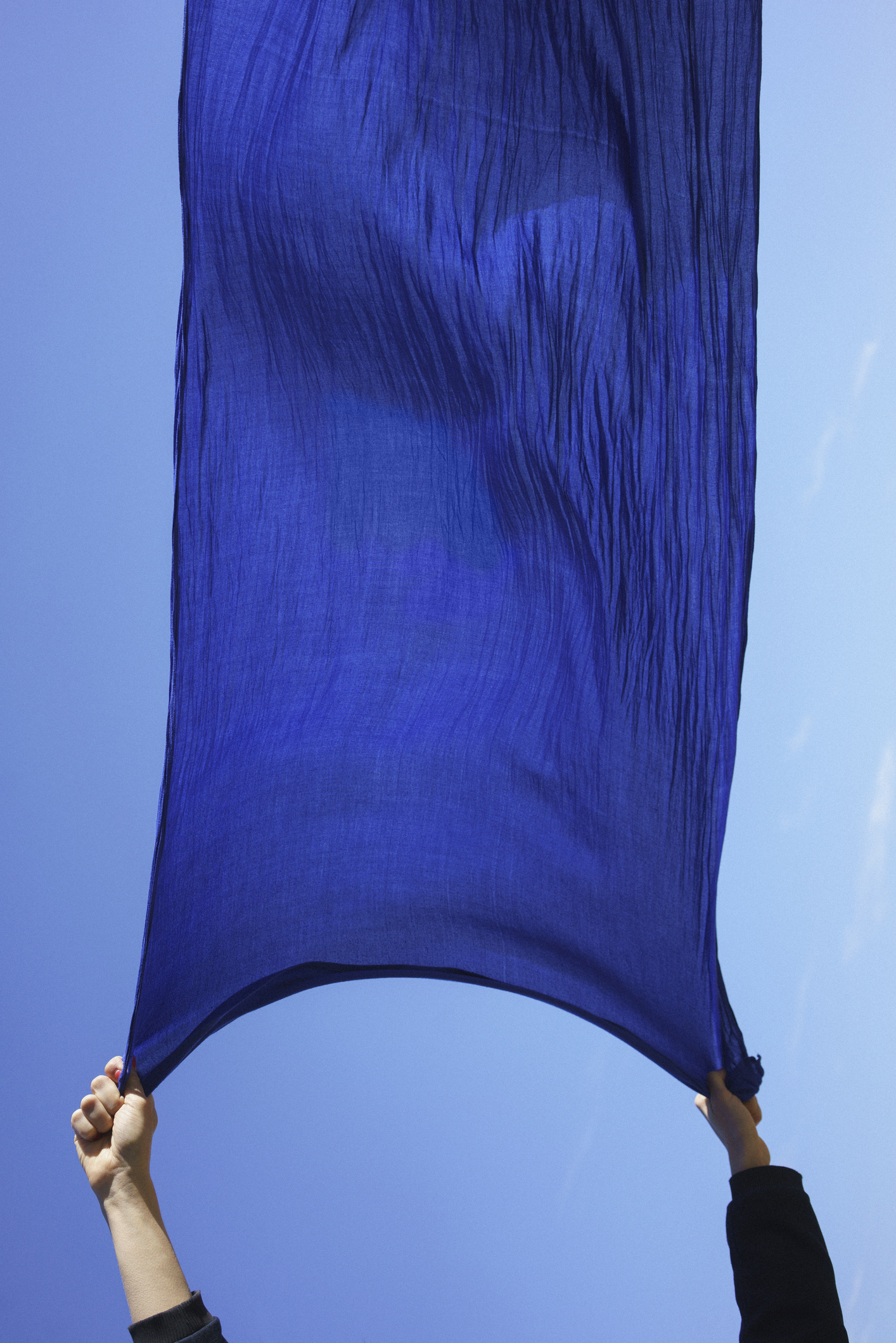 Cropped hands of woman holding blue sarong against clear sky fine art photography